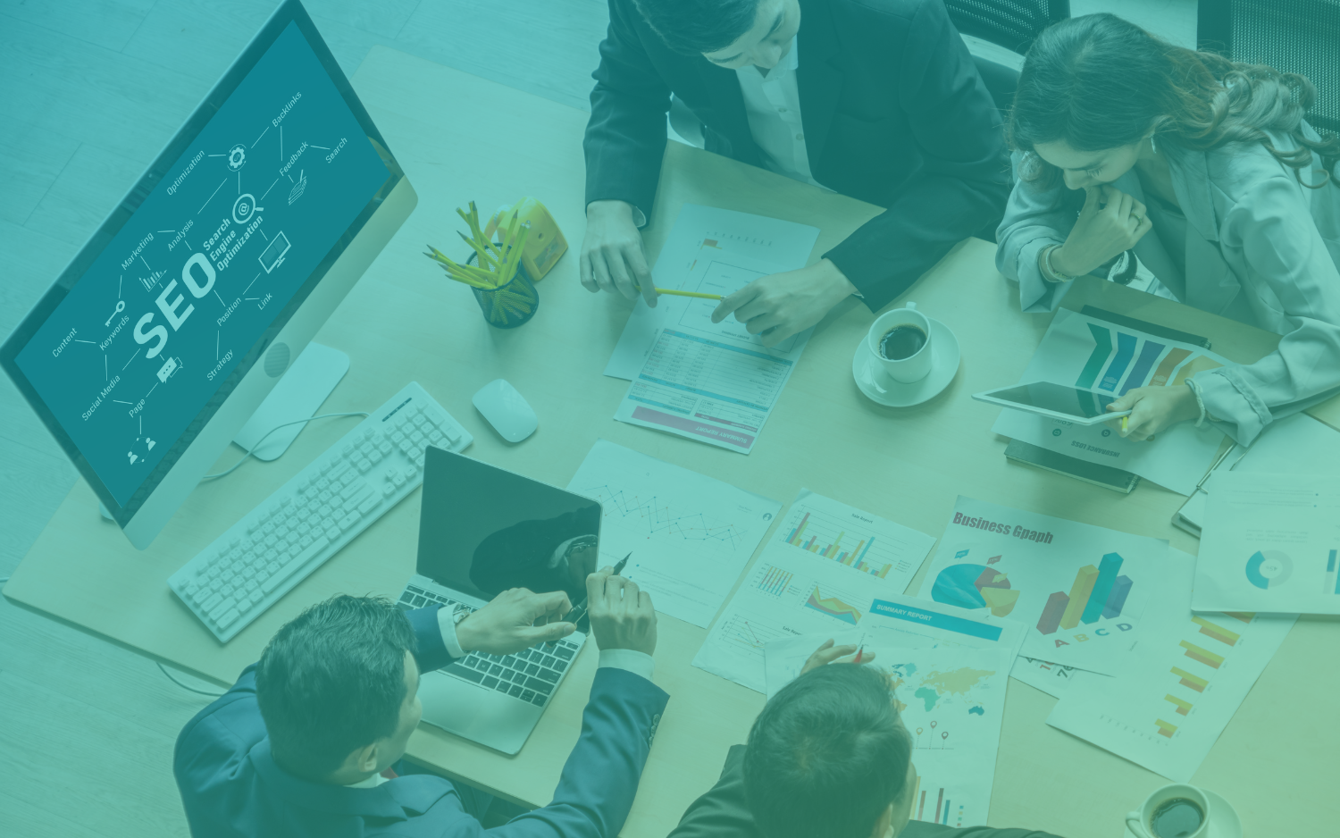 Ultimate Guide to Content Marketing for SEO Aerial image of four people working at a desk on an SEO plan. They are surrounded by laptops, a desktop computer, papers, and a cup.